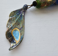 Artisan necklace has a butterfly wing in shades of aqua, yellow, purple