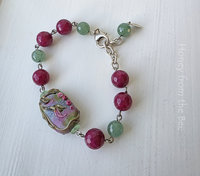 Floral bracelet features lampwork focal and beads of green and dark rose