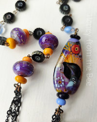 Statement necklace features crow lampwork in purple, orange and blue