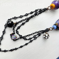 black chain dangles from crow necklace