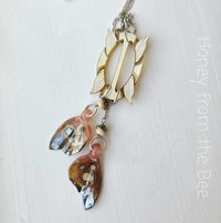 Butterfly necklace features lampworked butterfly wings in pink and an antique MOP buckle