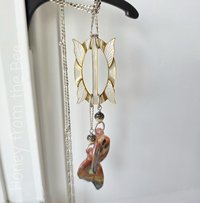 Butterfly Wings dangle from an antique mother of pearl buckle in this unique necklace