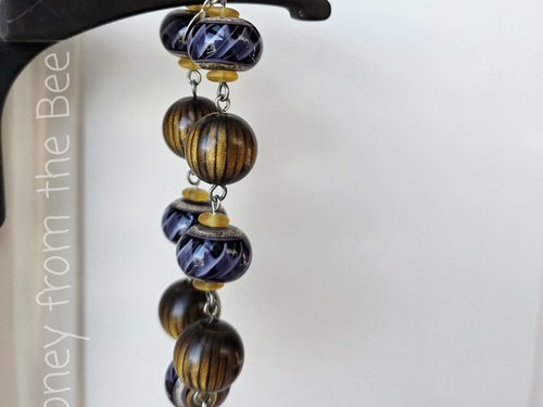 Purple ribbon bracelet features lampwork and wood beads
