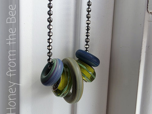 Artisan necklace features blue and green lampwork in matte and shiny finishes