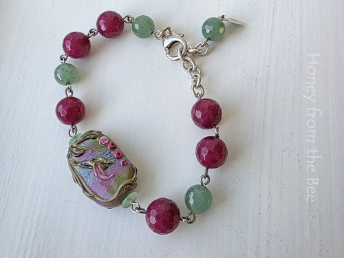 Floral bracelet features lampwork focal and beads of green and dark rose