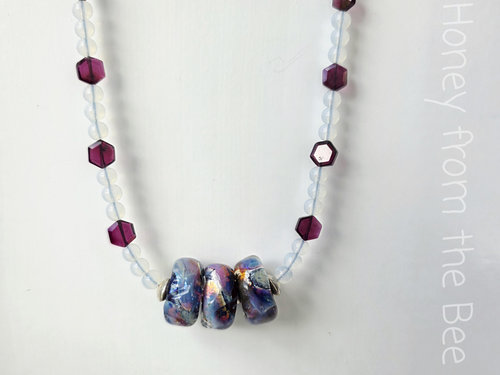 Red and blue necklace features artisan glass and garnet