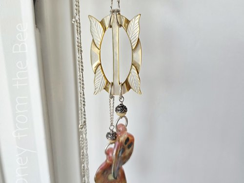Butterfly Wings dangle from an antique mother of pearl buckle in this unique necklace